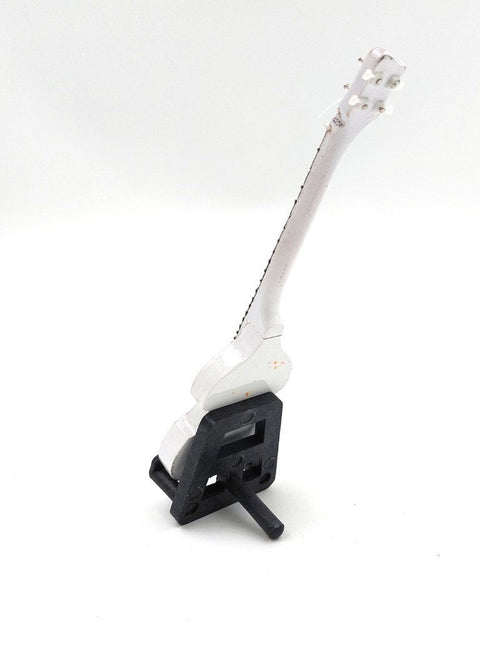 Miniatiūrinė gitara balta ant juodo plastikinio stovo, fotografuota iš priekio-šono, kolekcinė ekspozicijai