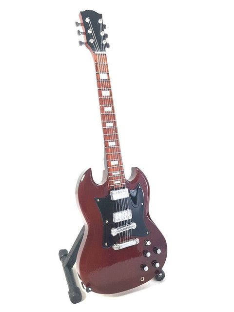 Elektrinė gitara bordo blizgio korpuso, juodu pickguardu ir trimis chromuotais humbuckeriais, stovinti atramoje