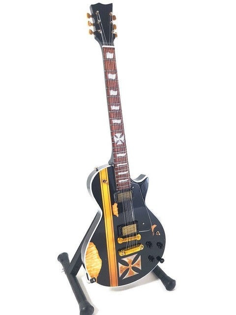 Elektrinė gitara juoda su ryškia geltona juosta ir auksinėmis detalėmis, vienpusis korpusas ant stovo, parodyta iš priekio