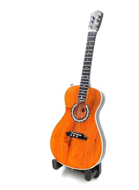 Gitara parlor dydžio su natūralia oranžine medžio apdaila, dekoratyvia rozetė ir juodu grifu, stovinti ant stovelio