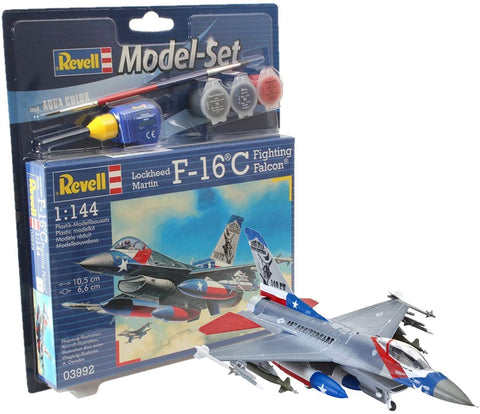 F-16C modelis Revell 1:144, surinktas ir dažytas patriotinėmis raudona‑mėlyna‑balta spalvomis, prie pakuotės su dažais ir teptuku.