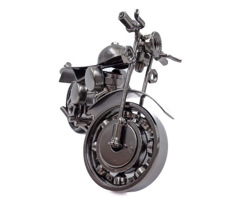 Miniatiūrinis metalinis motociklas tamsiai pilkos spalvos, artimas priekinio rato kampinis planas, pabrėžia smulkias mechanines detales