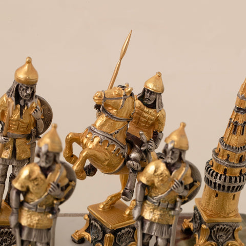 Šachmatų figūra raitelis iš auksuoto ir sidabruoto metalo, artimas planas su pakelta žirgo poza ir detaliu raižymu