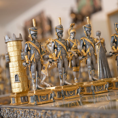 Šachmatai auksu ir sidabru sendinti metaliniai karių figūrėlės prie bokšto, artimas planas
