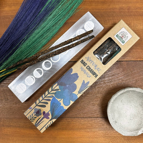 Nag Champa smilkalai, natūralios lazdelių versijos ant sidabrinio laikiklio šalia dekoratyvios kraft dėžutės