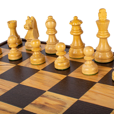Šachmatų rinkinys iš šviesios medienos ant kontrastingos tamsiai ir šviesiai rudos lentos, kampinis planas