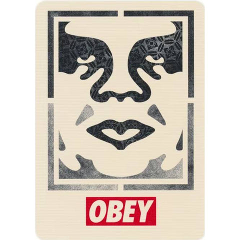 OBEY plakatas kremine fone su juodu stilizuotu veidu ir ryškiu raudonu logotipu apačioje, minimalistinis stilius