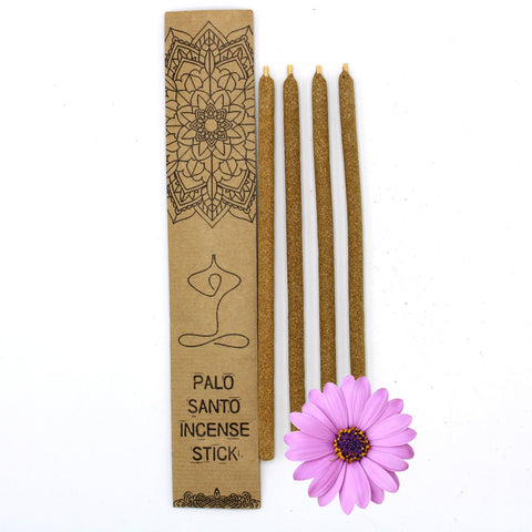 Palo Santo smilkalai – keturios bronzinės lazdelės prie kraft dėžutės su rožine gėle, išdėstytos iš viršaus