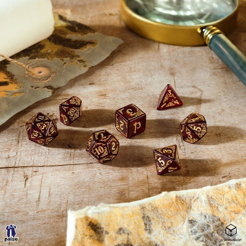 Kauliukai RPG 7 dalių rinkinys, bordo su auksiniais skaitmenimis, Paizo/Q Workshop variantas, matomas iš viršaus ant medinio stalo