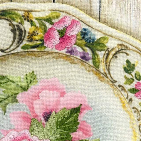 Porcelianinė lėkštė su rožinėmis gėlėmis ir smulkia auksine briauna, artima krašto detalė pabrėžia raštą ir spalvas