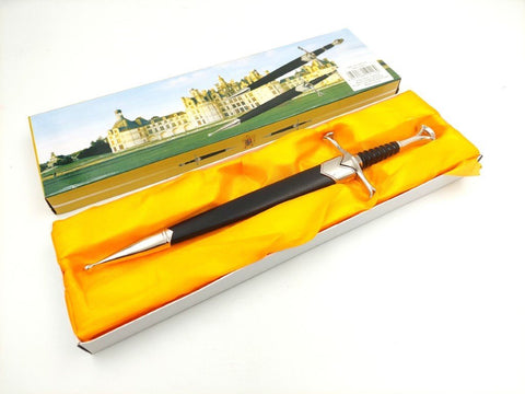 Dolkis su juodu kovanų ir sidabrine karda rankena, pristatomas horizantaliai dėžutėje su geltonu pamušalu, iš viršaus matomas