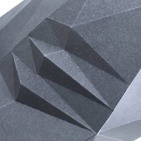 3D sienų panelė juodos spalvos artimas planas, matomos geometrinės sulankstytos briaunos ir grūdėta popieriaus tekstūra