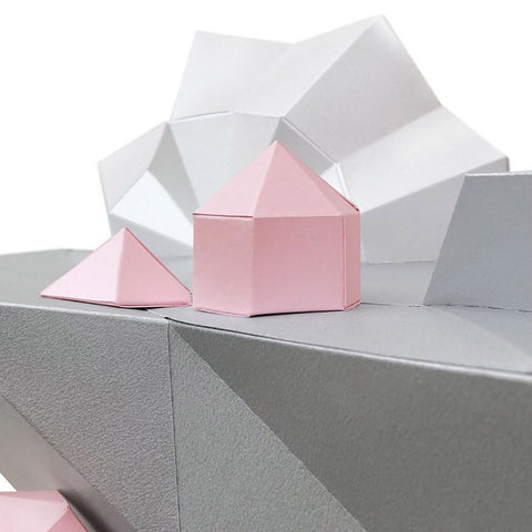 Dovanų dėžutė maža rožinė šešiakampė su piramidiniu dangteliu, rodoma iš šono ant pilko origami fono