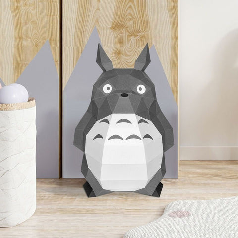 Pilkas geometrinis Totoro popierinis modelis, priekinis vaizdas ant medinio fono, dekoratyvi statoma figūrėlė unikaliu facetuotu dizainu