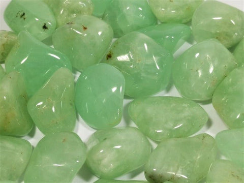 Aventurinas — šviesiai žali, poliruoti tumbled akmenukai (~20–30 mm), arti fiksuotas kadravimas pabrėžia blizgančius paviršius ir natūralias intarpas