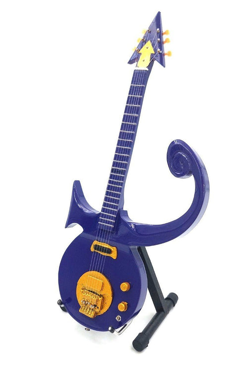Elektrogitara unikali violetinė, įkvėpta simbolio formos korpuso su auksinėmis detalėmis, pateikta ant stovelio iš priekio-dešinios pusės