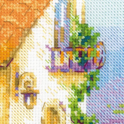 Kryželių rinkinys – artimas siuvinėjimo fragmentas, rodantis ryškius violetinius ir žalius siūlus ant pajūrio namelio balkono tekstūros