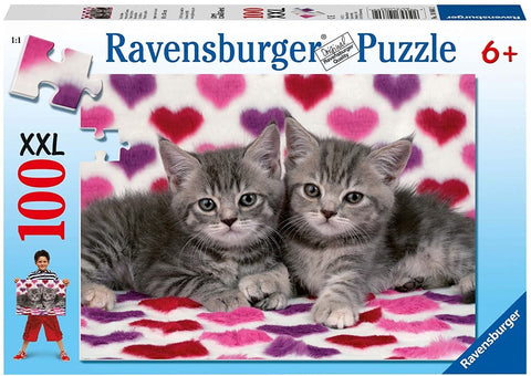 Dėlionė Ravensburger 100 dalių XXL su dviem pilkais kačiukais, gulintais ant baltai‑rožinio fono su spalvotomis širdelėmis