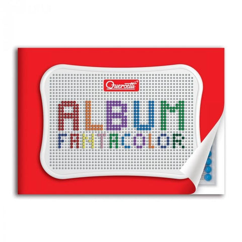 Mozaikos rinkinys Quercetti Album Fantacolor — baltas perforuotas dangtelis ant ryškaus raudono fono, atlenktas kampas su matomais mėlynais smeigtukais