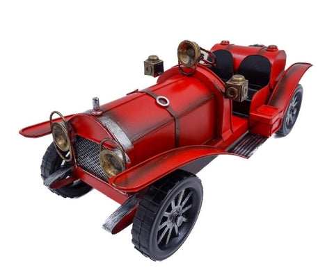 Retro metalinis automobilio modelis, ryškiai raudonas, atviri dvivietis salonas ir žalvariniai žibintai, priekinis kampas