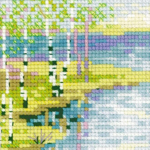 Siuvinėjimo rinkinys — arti parodytas kryželių tekstūros fragmentas su žaliais, geltonais ir mėlynais siūlais, rodomas detalus dygsnių raštas