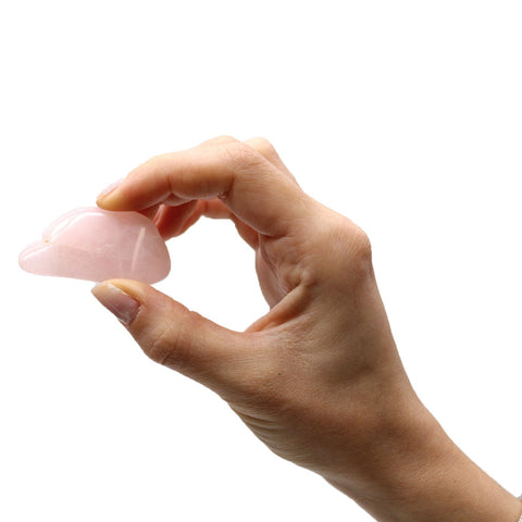 Rožinio kvarco gua sha masažo akmuo, mažas (~4 cm) šoninis variantas, laikomas pirštais, parodo kontūrą ir profilį