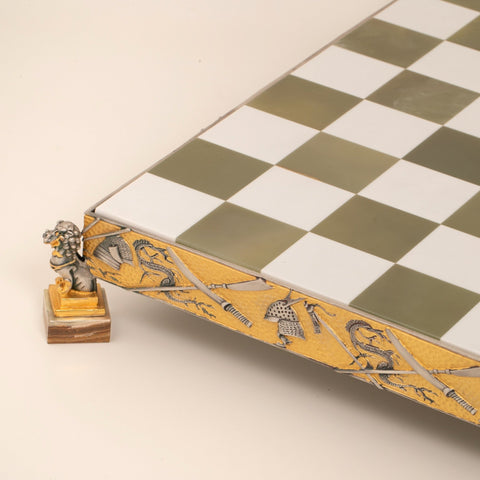 Šachmatų lenta su žaliai baltu dėmelių raštu, dekoratyvia auksine briauna ir liūto kojelės kampu