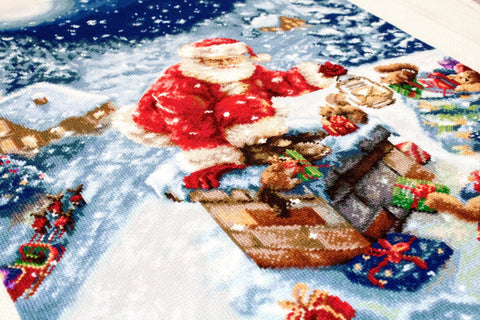 Kalėdinis audinys su Seneliu, ryškiai raudona ir mėlyna, kampinis makro kadravimas parodo siūlių faktūrą ir dovanų motyvus