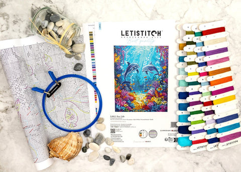 Siuvinėjimo rinkinys LETISTITCH „Sea Life“ su delfinų piešiniu, spalvotomis siūlėmis, schema ir mėlynu lankeliu ant stalviršio