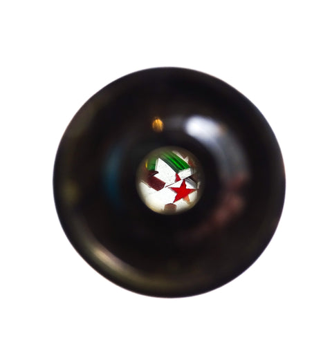 Kaleidoskopas juodo korpuso žiūroninio kampo centre matyti raudona žvaigždė ir spalvotos stiklo detalės