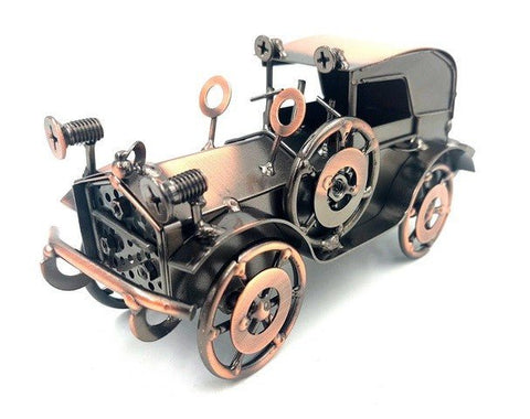 Retro metalinis automobilio modelis, juodos ir vario spalvų, smulkus rankų darbo stalo suvenyras, matomas iš priekinio kairio kampo