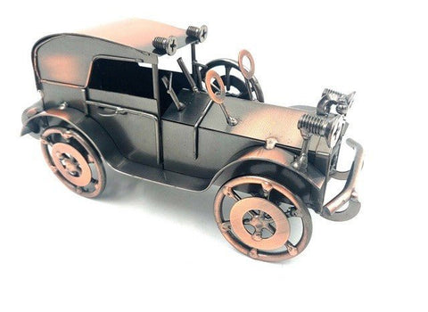 Metalinis senovinis automobilio modelis tamsiai pilkas su vario akcentais, matomas iš priekinio dešinio 3/4 kampo, stilinga stalviršio dekoracija arba dovana