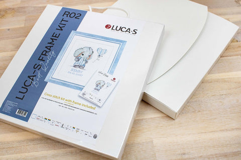 Kryželių rinkinys Luca‑S su baltu rėmu ir pakuote, parodytas iš viršaus kampo; komplekte rėmas, audinys ir schema