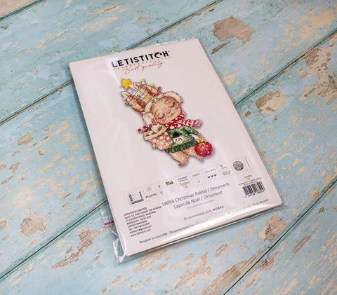Siuvinėjimo rinkinys LETISTITCH — kalėdinis triušiuko žaisliukas pakuotėje, fiksuotas iš viršaus ant žydros medinės lentos
