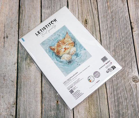 Siuvinėjimo rinkinys Letistitch su plaukiojančio oranžinio kačiuko piešiniu, uždarytas plastikinėje pakuotėje ant medinės lentos