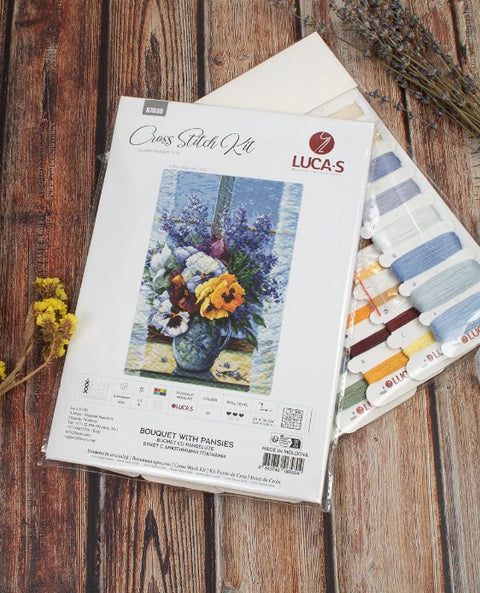 Kryželių rinkinys LUCA‑S 'Bouquet with Pansies' su instrukcija ir spalvotais siūlais, rodoma pakuotė su siūlų palete.