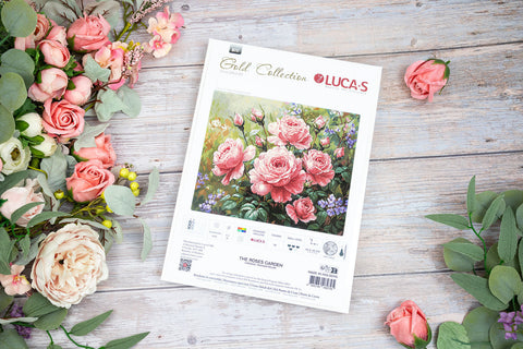 Kryželių rinkinys LUCA‑S The Roses Garden su rožinių rožių raštu ant baltos pakuotės, medinio stalo fone