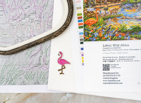 Skaičiuota kryželiu rinkinys Wild Africa – rodoma simbolių schema, spalvų paletė, siūlų lankelis ir rožinis flamingo smeigtukas