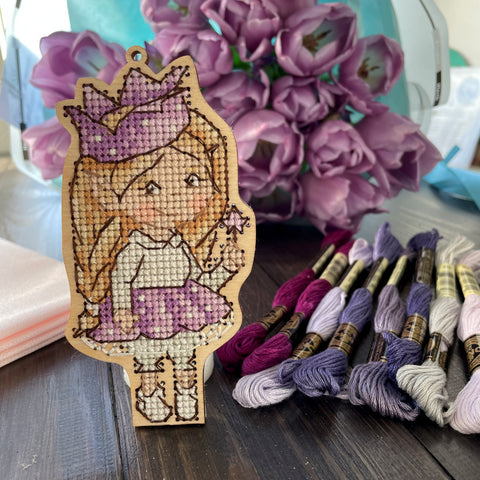 Siuvinėta medinė sagė su princese, violetinių tonų siūlais ir ryškiu kontūru, artimas frontalus planas