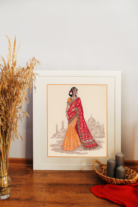 Siuvinėtas paveikslas — rėmuota Indijos moteris raudona‑oranžine sari, 30×40 cm, minimalistinis sienos akcentas