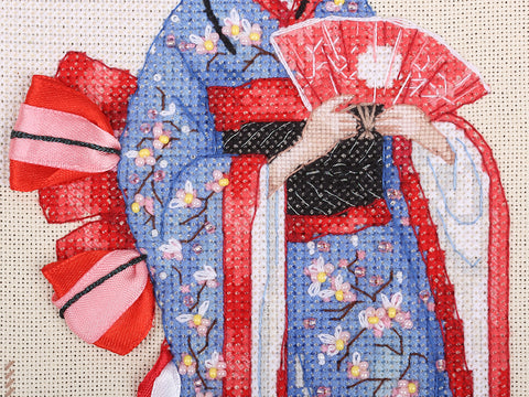 Siuvinėtas geišos paveikslas artimas planas: mėlyno kimono gėlės su karoliukais, raudonas vėduoklės ir kaspino akcentas