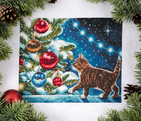 kryželiu siuvinys rudas dryžuotas katinas prie snieguotos eglutės su raudonais ir mėlynais burbulais, 25×20 cm artimas kampas
