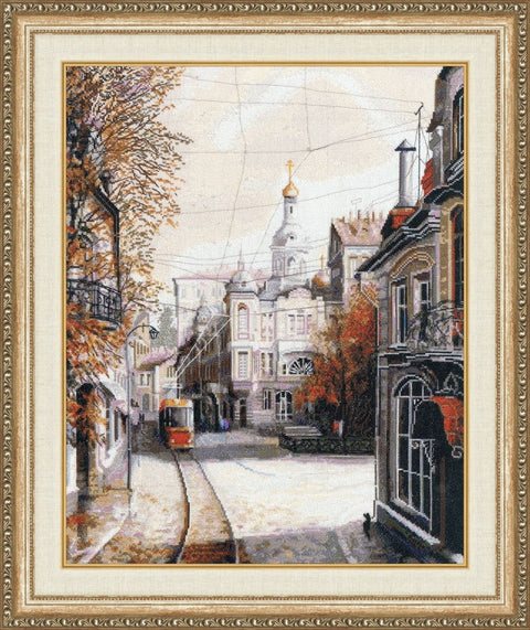Siuvinėtas miesto peizažas kryželiu, rudos ir smėlio tonų, su tramvajumi ir auksiniu bažnyčios kupolu, 40×50 cm rėme