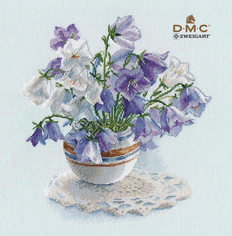 Kryželių rinkinys DMC Zweigart: violetinės ir baltos varpelės vazoje su dryžuotu indeliu ant nėriniuotos servetėlės