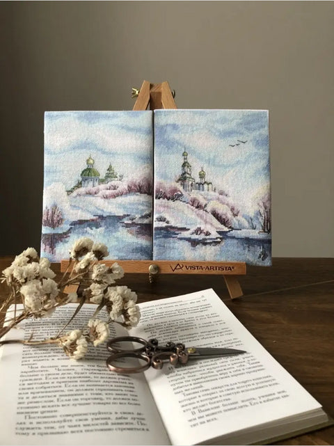 Mini drobė diptichas Vista‑Artista žiemiškas peizažas mėlynais tonais ant stovo, stilizuotas su atversta knyga ir žirklėmis