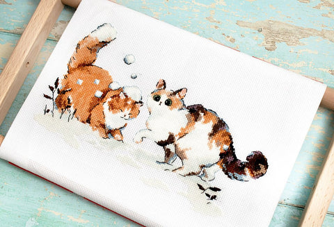 Kryželių rinkinys, balta drobė, artimas kampas su dviem margomis katėmis sniege ir ryškiomis siūlių detalėmis