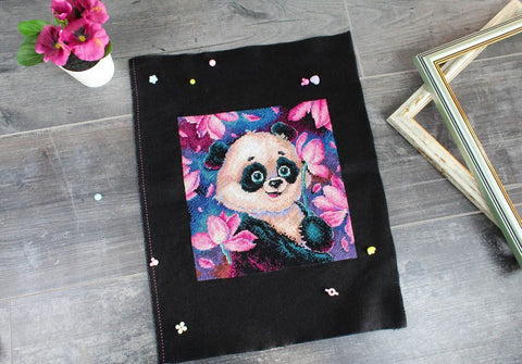 Kryželių rinkinys ant juodos Aida: ryški panda tarp rožinių žiedų, paruošta rėminimui, 30×40 cm
