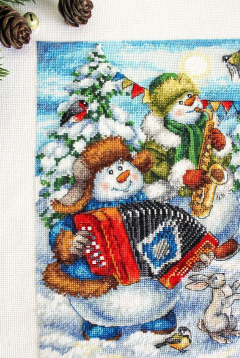 Siuvinėjimo rinkinys su žiemišku motyvu, artimas kairės pusės fragmentas – sniego žmogus groja armonika, matomi paukščiai ir dekoracijos