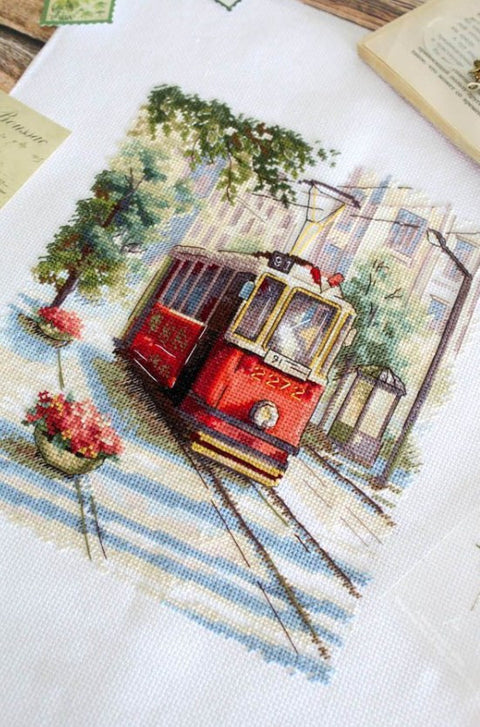 Kryželiu siuvinėtas paveikslas: raudonas tramvajus miesto gatvėje, detalus artinis kampas ir spalvų variantas