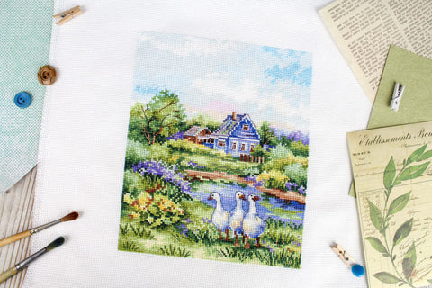 kryželių siuvinys su mėlynu nameliu ir trimis žąsimis ant žolės, parodo baigtą 30×30 cm dizainą ir spalvų detalumą